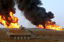 燃え上がる石油パイプラインのそばを進む米軍の装甲車＝ＡＰ