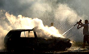 １９日、バクダット市内で自動車爆弾が爆発し、消火作業をする消防士＝ＡＰ