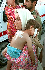 イラク中部ラマディで１３日、米軍と武装勢力との衝突の巻き添えとなり、砲弾の破片でけがをした男児を抱く母親＝ＡＰ
